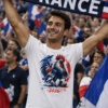 Combine les deux images jointes pour que l’homme porte exactement le t-shirt fourni. Le design du t-shirt doit rester 100 % identique (texte, couleurs, proportions, placement — aucune modification). CHANGE le visage de l’homme par un visage réaliste différent. Crée une ambiance cohérente avec le message du t-shirt. Photo ultra réaliste, lumière naturelle, rendu professionnel, qualité 4K. Le texte du t-shirt doit rester parfaitement lisible et inchangé.